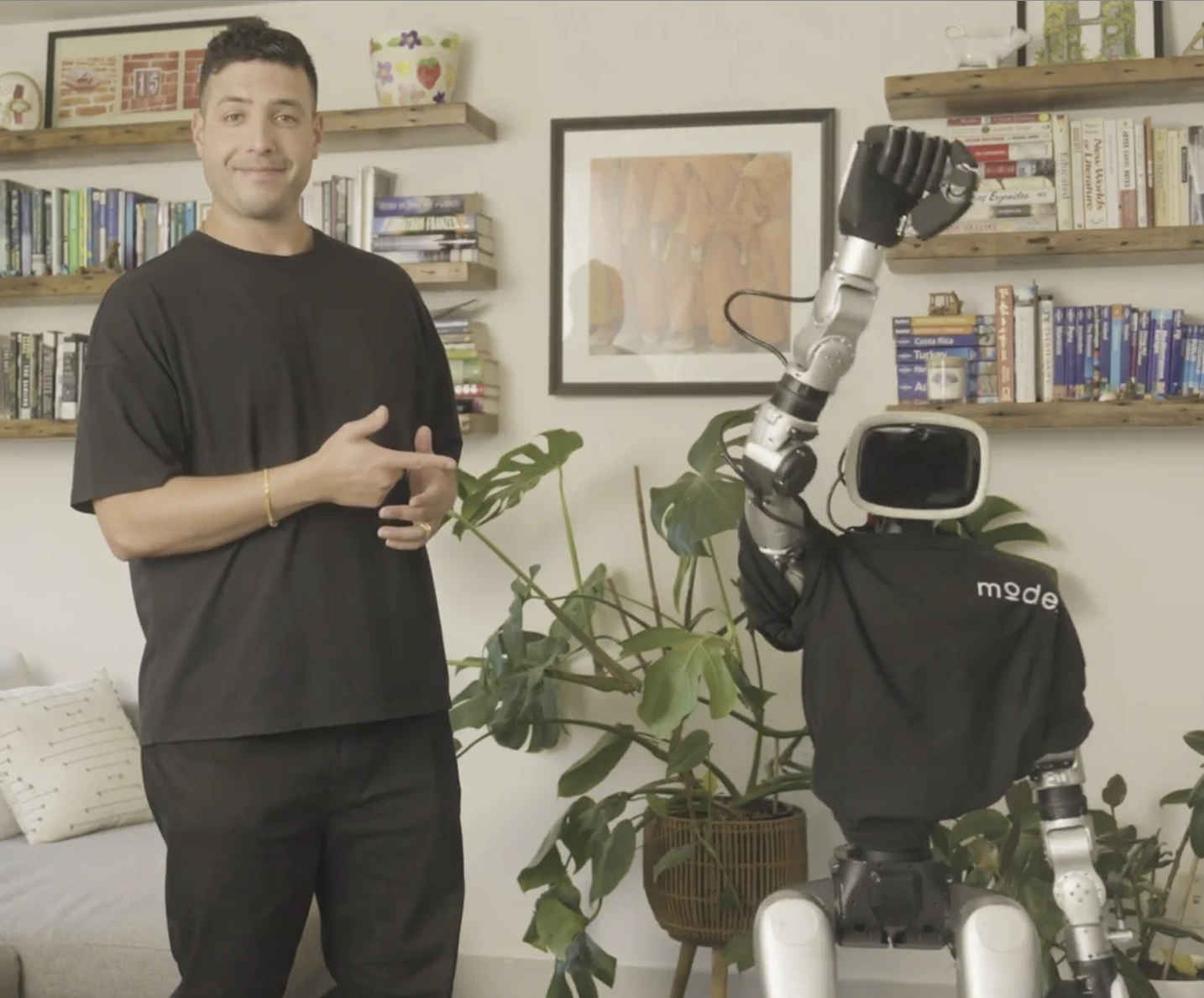 Mode CEO Dan Novaes standing beside a robot wearing a Mode shirt